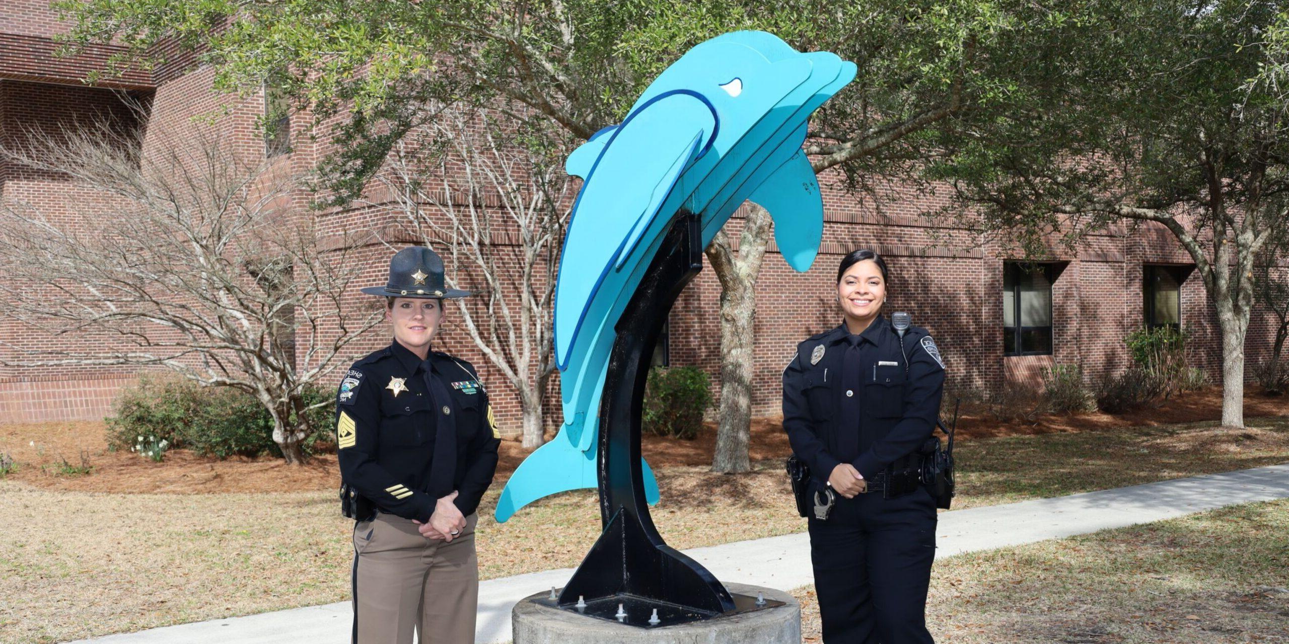 两名执法人员站在海豚雕像附近